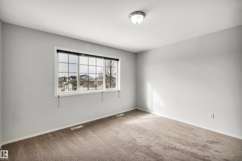 Carpeted spare room featuring baseboards and a textured ceiling - 3401 47 Street, Beaumont, AB - Indoor Photo Showing Other Room