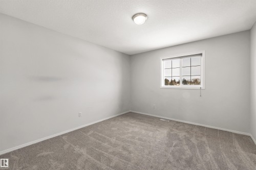 Carpeted empty room with baseboards and a textured ceiling - 3401 47 Street, Beaumont, AB - Indoor Photo Showing Other Room