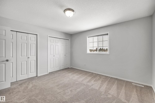 Unfurnished bedroom featuring two closets, carpet flooring, and a textured ceiling - 3401 47 Street, Beaumont, AB - Indoor Photo Showing Other Room