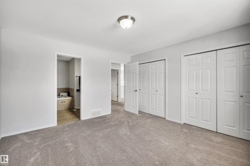 Unfurnished bedroom with two closets, carpet flooring, and connected bathroom - 3401 47 Street, Beaumont, AB - Indoor