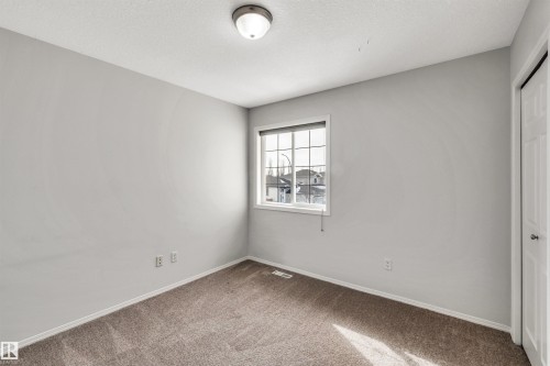 Unfurnished bedroom featuring a closet, carpet, and a textured ceiling - 3401 47 Street, Beaumont, AB - Indoor Photo Showing Other Room