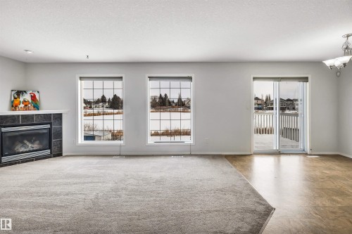 Unfurnished living room with healthy amount of natural light, a fireplace, and a textured ceiling - 3401 47 Street, Beaumont, AB - Indoor Photo Showing Living Room With Fireplace