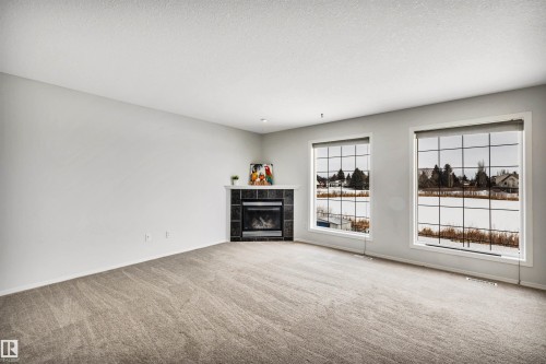 Unfurnished living room featuring carpet flooring, a tile fireplace, and a textured ceiling - 3401 47 Street, Beaumont, AB - Indoor With Fireplace