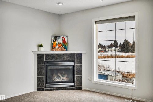Detailed view of carpet flooring and a tile fireplace - 3401 47 Street, Beaumont, AB - Indoor With Fireplace