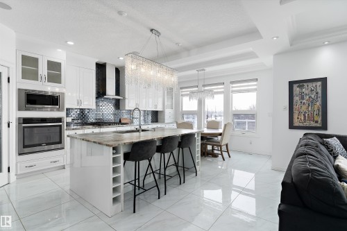 Kitchen featuring glass insert cabinets, stainless steel appliances, dark stone counters, open floor plan, and tasteful backsplash - 1242 Starling Drive, Edmonton, AB - Indoor Photo Showing Kitchen With Upgraded Kitchen
