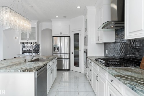 Kitchen with stainless steel appliances, dark stone counters, white cabinets, and glass fronted cabinets - 1242 Starling Drive, Edmonton, AB - Indoor Photo Showing Kitchen With Upgraded Kitchen