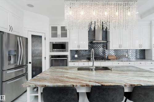 Kitchen featuring light stone countertops, stainless steel appliances, white cabinetry, a breakfast bar, and glass fronted cabinets - 1242 Starling Drive, Edmonton, AB - Indoor Photo Showing Kitchen With Upgraded Kitchen