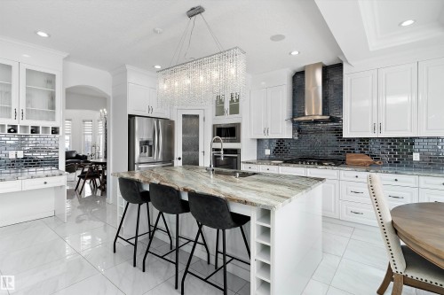 Kitchen with glass insert cabinets, backsplash, light stone countertops, and arched walkways - 1242 Starling Drive, Edmonton, AB - Indoor Photo Showing Kitchen With Upgraded Kitchen