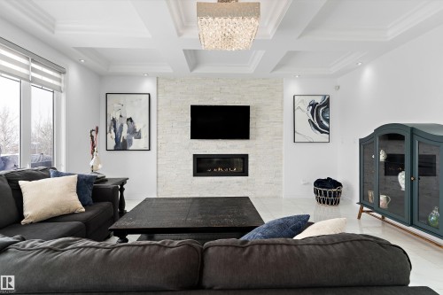 Living area with coffered ceiling, a fireplace, suspended lighting, and ornamental molding - 1242 Starling Drive, Edmonton, AB - Indoor Photo Showing Living Room With Fireplace