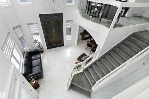 Entryway featuring a high ceiling, a fireplace, plenty of natural light, light tile patterned flooring, and a chandelier - 1242 Starling Drive, Edmonton, AB - Indoor Photo Showing Other Room With Fireplace