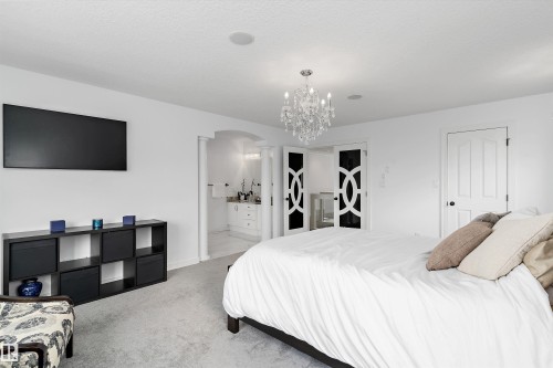 Carpeted bedroom with arched walkways, ensuite bath, and hanging lights - 1242 Starling Drive, Edmonton, AB - Indoor Photo Showing Bedroom