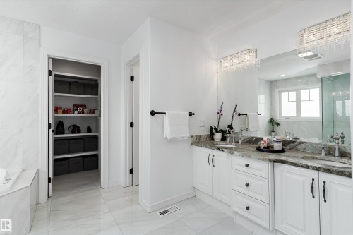 Full bath featuring double vanity, a walk in closet, light marble finish floors, a bath, and a shower - 1242 Starling Drive, Edmonton, AB - Indoor Photo Showing Bathroom