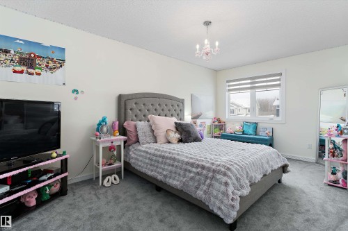 Bedroom with light carpet, a textured ceiling, and a chandelier - 1242 Starling Drive, Edmonton, AB - Indoor Photo Showing Bedroom