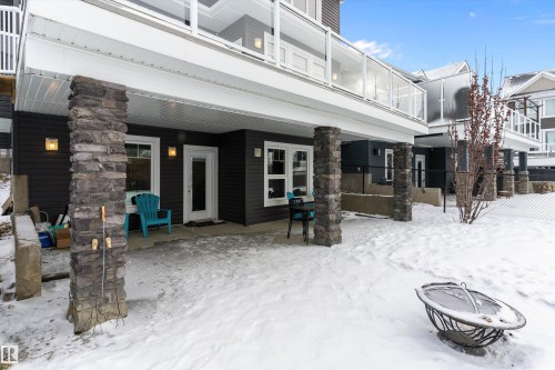 Snow covered back of property featuring a patio, a balcony, and stone siding - 1242 Starling Drive, Edmonton, AB - Outdoor