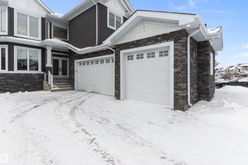 View of snowy exterior featuring french doors, stone siding, and a garage - 1242 Starling Drive, Edmonton, AB - Outdoor