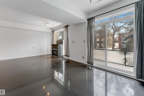 Unfurnished room with baseboards and a glass covered fireplace - 102 10711 83 Avenue, Edmonton, AB - Indoor Photo Showing Other Room