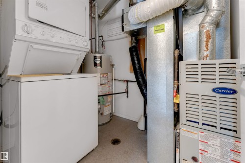 Utilities featuring heating unit, water heater, and stacked washing machine and dryer - 102 10711 83 Avenue, Edmonton, AB - Indoor Photo Showing Other Room
