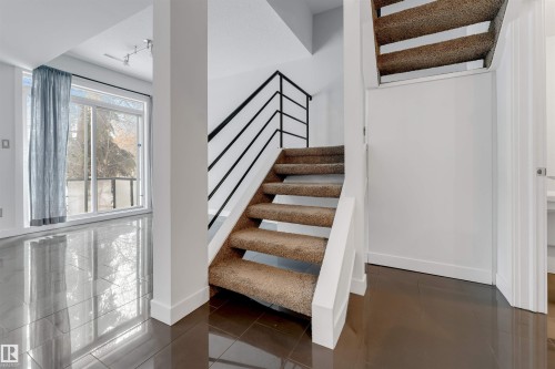 Stairway with tile patterned floors and track lighting - 102 10711 83 Avenue, Edmonton, AB - Indoor Photo Showing Other Room