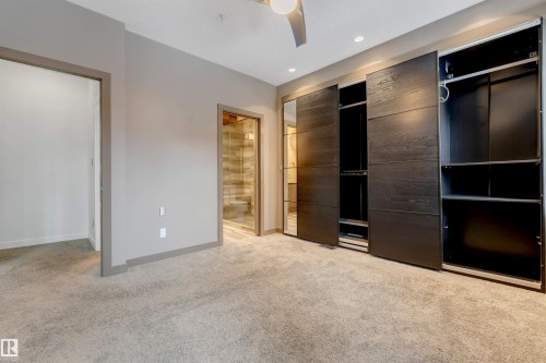 Unfurnished bedroom featuring light colored carpet, a ceiling fan, two closets, and ensuite bathroom - 102 10711 83 Avenue, Edmonton, AB - Indoor Photo Showing Other Room