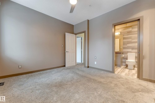 Unfurnished bedroom with light colored carpet, a ceiling fan, and connected bathroom - 102 10711 83 Avenue, Edmonton, AB - Indoor Photo Showing Other Room