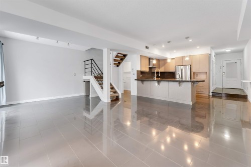 Kitchen with a kitchen bar, dark tile patterned flooring, stainless steel refrigerator with ice dispenser, pendant lighting, and a peninsula - 102 10711 83 Avenue, Edmonton, AB - Indoor Photo Showing Kitchen