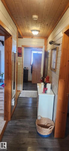 Corridor featuring wood ceiling, wood walls, and dark wood-type flooring - 5216 - 53 Avenue, Clyde, AB - Indoor
