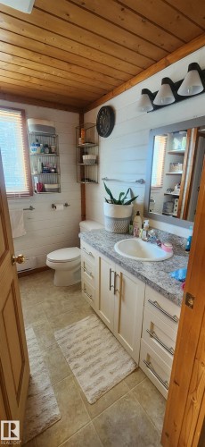 Half bathroom featuring wood ceiling, vanity, wooden walls, and light tile patterned floors - 5216 - 53 Avenue, Clyde, AB - Indoor Photo Showing Bathroom