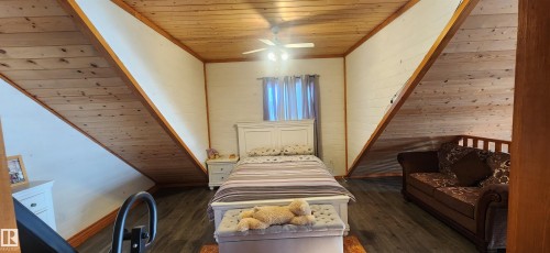 Bedroom with wooden ceiling, dark wood-type flooring, wood walls, and ceiling fan - 5216 - 53 Avenue, Clyde, AB - Indoor Photo Showing Other Room