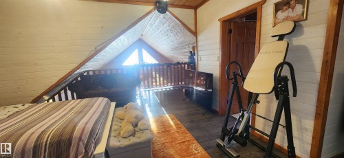 Bedroom featuring vaulted ceiling, wood ceiling, dark wood-type flooring, wood walls, and a crib - 5216 - 53 Avenue, Clyde, AB - Indoor Photo Showing Other Room