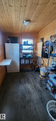 Interior space featuring wooden walls, wooden ceiling, and dark wood-style floors - 5216 - 53 Avenue, Clyde, AB - Indoor