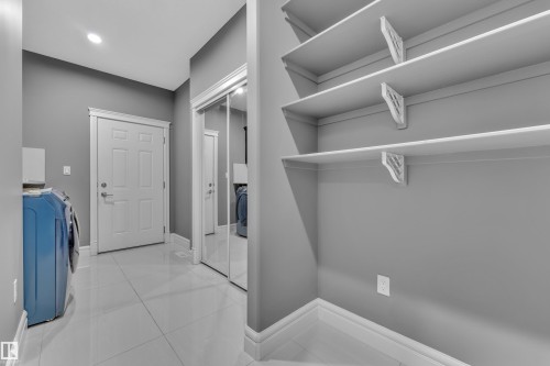 Laundry room with light tile patterned floors and washing machine and clothes dryer - 2612 Adam Court Sw, Edmonton, AB - Indoor With Storage