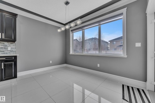 Unfurnished dining area featuring ornamental molding, light tile patterned floors, and a textured ceiling - 2612 Adam Court Sw, Edmonton, AB - Indoor Photo Showing Other Room