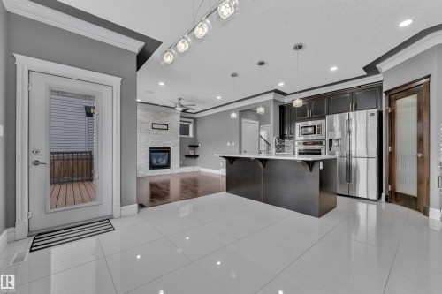 Kitchen with a breakfast bar, ornamental molding, a center island with sink, stainless steel appliances, and open floor plan - 2612 Adam Court Sw, Edmonton, AB - Indoor Photo Showing Kitchen With Upgraded Kitchen