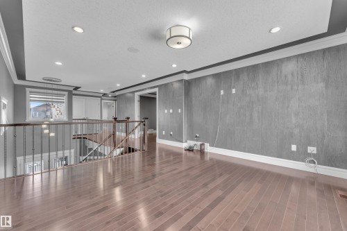 Empty room featuring ornamental molding, dark wood-style flooring, recessed lighting, and a textured ceiling - 2612 Adam Court Sw, Edmonton, AB - Indoor Photo Showing Other Room