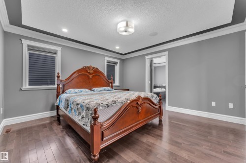 Bedroom with crown molding, recessed lighting, dark wood-style floors, and a textured ceiling - 2612 Adam Court Sw, Edmonton, AB - Indoor Photo Showing Bedroom