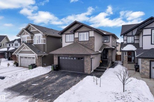 Craftsman house featuring asphalt driveway, a residential view, a garage, and stone siding - 2612 Adam Court Sw, Edmonton, AB - Outdoor With Facade