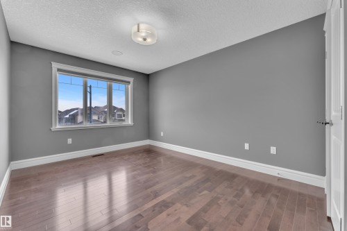 Spare room with dark wood-style flooring and a textured ceiling - 2612 Adam Court Sw, Edmonton, AB - Indoor Photo Showing Other Room