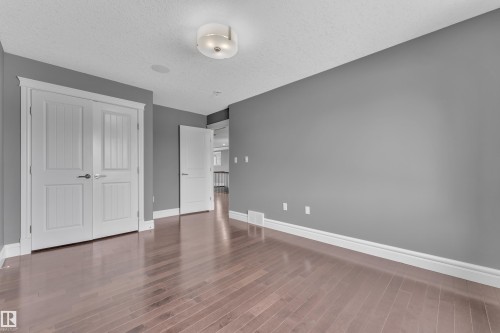 Unfurnished bedroom with a textured ceiling, a closet, and dark wood-style flooring - 2612 Adam Court Sw, Edmonton, AB - Indoor Photo Showing Other Room