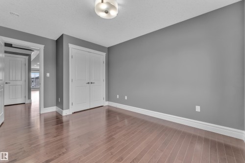 Unfurnished bedroom featuring a closet, dark wood finished floors, and a textured ceiling - 2612 Adam Court Sw, Edmonton, AB - Indoor Photo Showing Other Room