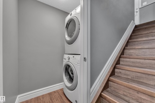 Laundry area featuring light wood-type flooring and stacked washing machine and dryer - 2612 Adam Court Sw, Edmonton, AB - Indoor Photo Showing Laundry Room
