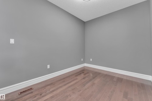 Spare room featuring dark wood-style floors and a textured ceiling - 2612 Adam Court Sw, Edmonton, AB - Indoor Photo Showing Other Room