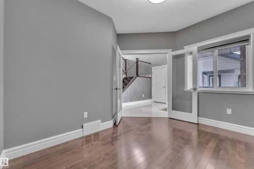 Unfurnished room featuring wood-type flooring and a textured ceiling - 2612 Adam Court Sw, Edmonton, AB - Indoor Photo Showing Other Room