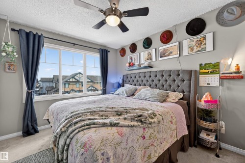 Bedroom with light colored carpet, a textured ceiling, and ceiling fan - 14 1140 Chappelle Boulevard, Edmonton, AB - Indoor Photo Showing Bedroom