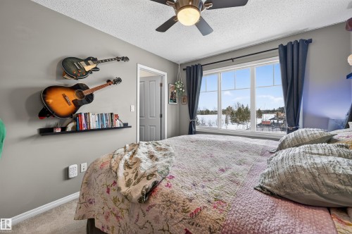 Carpeted bedroom with a textured ceiling and ceiling fan - 14 1140 Chappelle Boulevard, Edmonton, AB - Indoor Photo Showing Bedroom