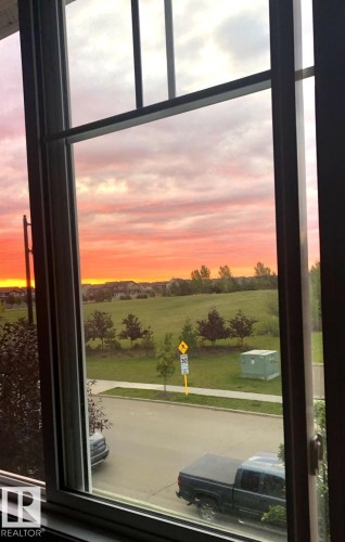 The property features a window providing a view of a green space, a street, and distant residences - 14 1140 Chappelle Boulevard, Edmonton, AB - Indoor Photo Showing Other Room