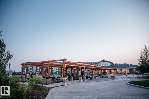 The property features a large pergola area with seating, a well-maintained lawn, and mature trees - 14 1140 Chappelle Boulevard, Edmonton, AB - Outdoor