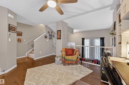Sitting room with dark wood-type flooring, a desk, a ceiling fan, and a textured ceiling - 14 1140 Chappelle Boulevard, Edmonton, AB - Indoor