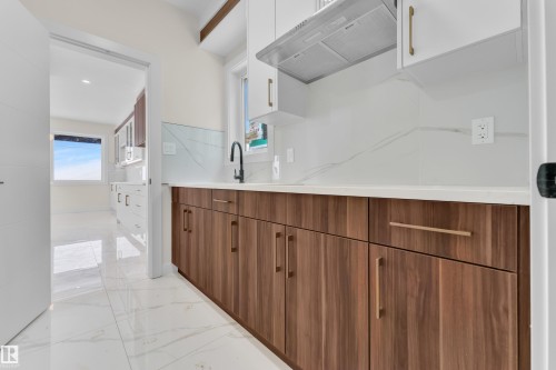 Dual tone kitchen featuring two tone color scheme, light marble finish floors, modern cabinets, recessed lighting, and decorative backsplash - 231 Crystal Creek Drive, Leduc, AB - Indoor Photo Showing Kitchen