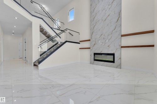 Unfurnished living room featuring a premium fireplace, a high ceiling, light marble finish flooring, and recessed lighting - 231 Crystal Creek Drive, Leduc, AB - Indoor Photo Showing Other Room