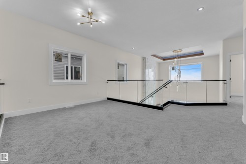 Spare room with hanging lights, a tray ceiling, and light carpet - 231 Crystal Creek Drive, Leduc, AB - Indoor Photo Showing Other Room